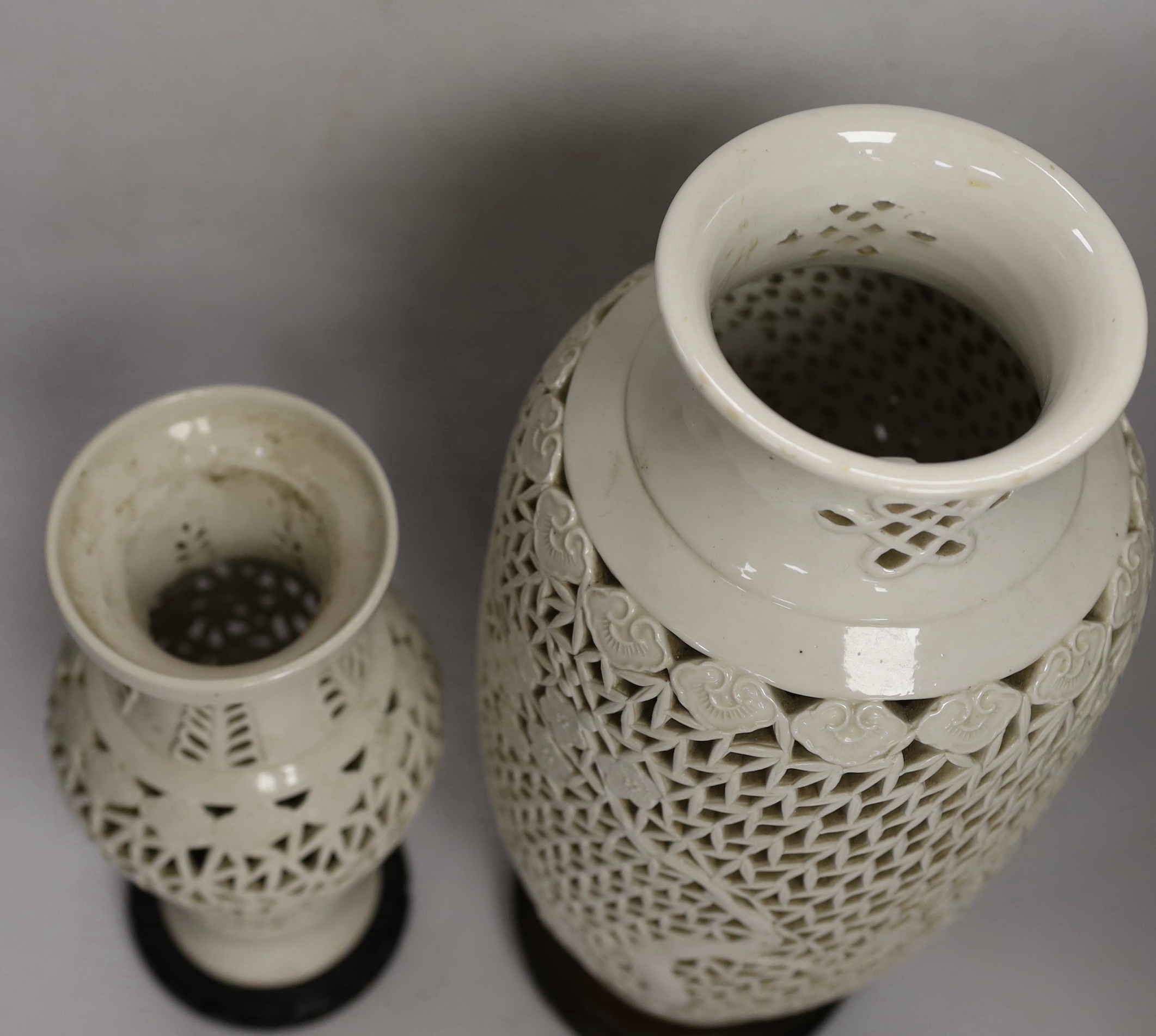 Two Chinese blanc de chine reticulated vase/lamps, on carved stands, largest 40cm high